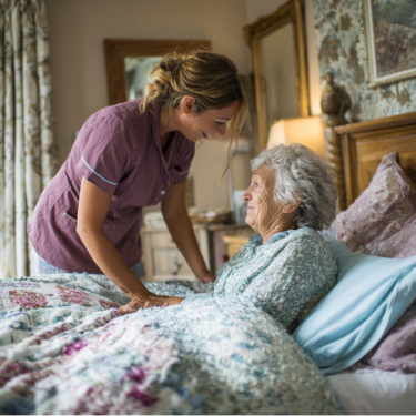 A home caregiver gently speaks with an elderly woman resting in bed, ensuring comfort and reassurance. This warm, peaceful setting reflects compassionate hospice care in Bartlesville, OK within a calm home environment.