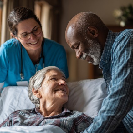 Hospice nurse and caregiver supporting elderly woman in bed, hospice care in Wichita KS