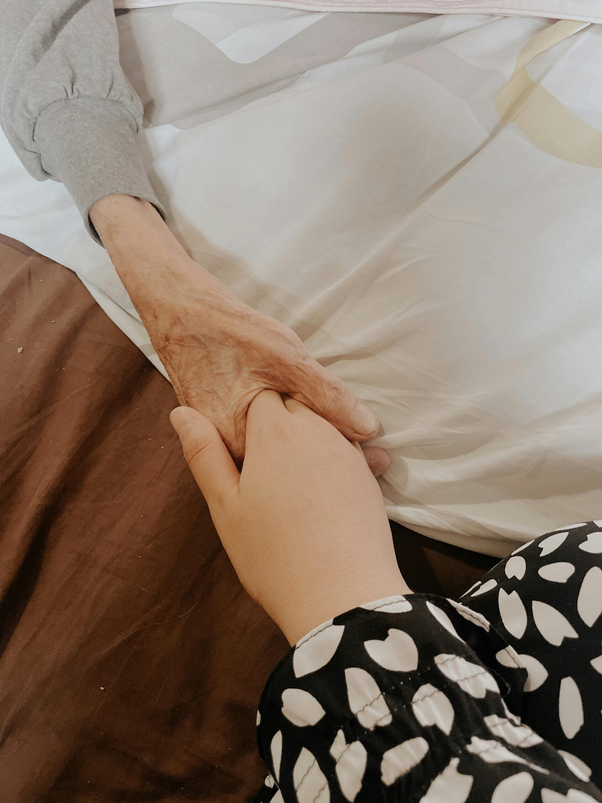 holding a hand of an elder as part of hospice care